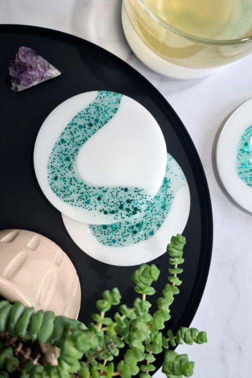 Ronde, witte Resin Art onderzetters met glitter groene swirls er doorheen.
