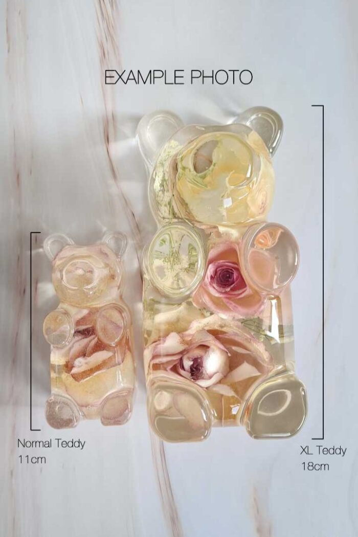 Foto van 2 resin beeldjes in de vorm van een Gummy beer met gedroogde bloemen erin. Een in het groot, en een in het klein. De afbeelding toont het grootte verschil van de beertjes.