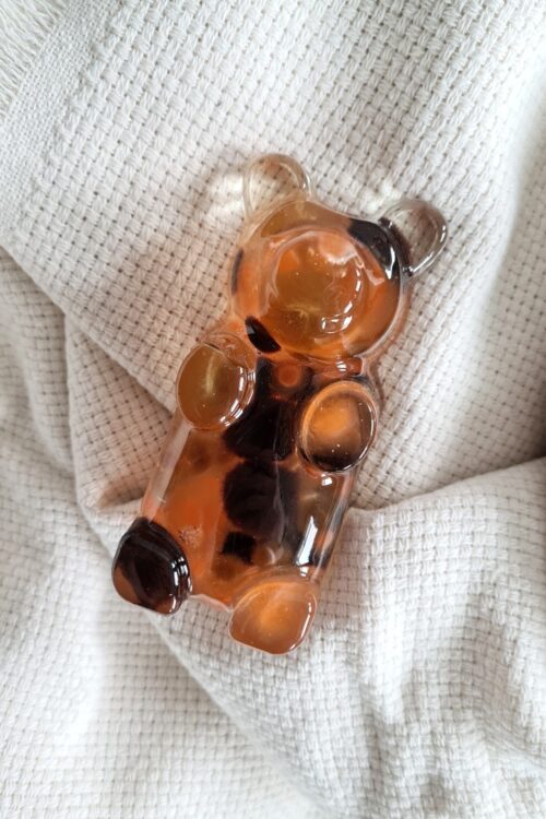 Gummy bear shaped statue, the Charming Teddy, is a handmade art piece from crystal clear resin with brown and black pompoms
