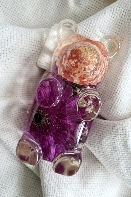 Charming Teddy, a luxurious gummy bear shaped artpiece made of crystal clear resin with orange and purple roses in it.