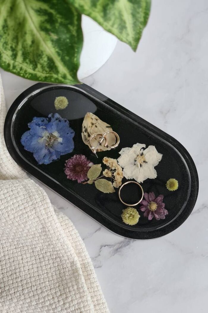 Oval trinket tray made from black epoxy with various colored flowers in it