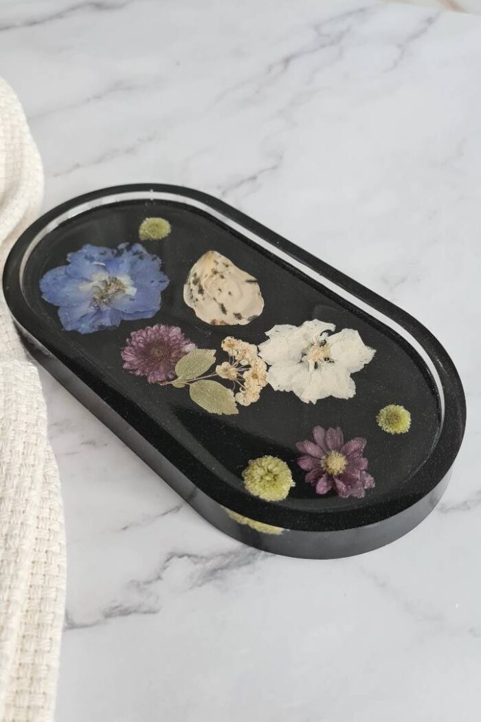 Oval trinket tray made from black epoxy with various colored flowers in it